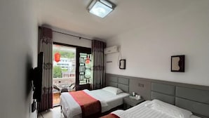 Camera d'albergo con due letti, una TV, un condizionatore e vista all'esterno.
