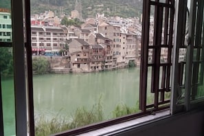 A view of a river with buildings along the banks, viewed through a window with a grid pattern. - Zhenyuan Yishan Yishui River View Homestay (Zhenyuan County)