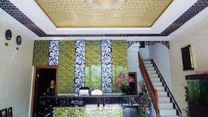 Un'area reception con un soffitto decorativo, una scala e un banco informazioni.