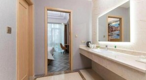 A hotel bathroom with a large mirror, a sink, and a herringbone-patterned floor. - Vienna Hotel (Suzhou)