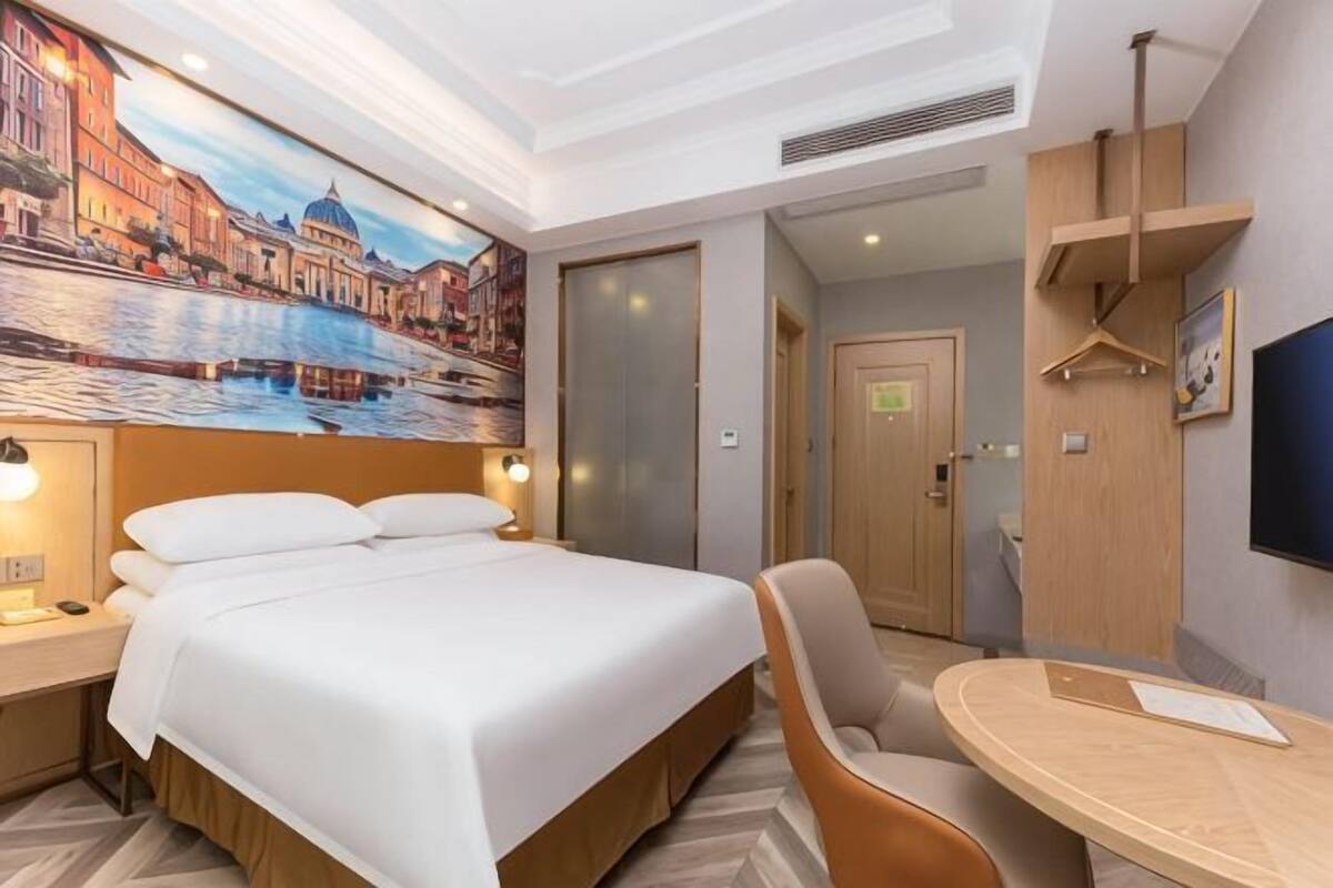 Une chambre d’hôtel avec un lit, une chaise, une table, un tableau et un téléviseur.