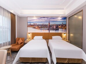 A hotel room with two beds, a chair, a small table, and a cityscape painting on the wall. - Vienna Hotel (Suzhou)