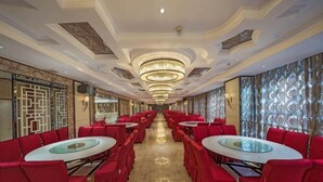 Eine Hotelhalle mit roten Stühlen und Tischen, einer Chandelier und einer Wand mit Muster.