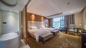 Ein modernes Hotelzimmer mit einem großen Bett, einer separaten Sitzecke, einem Schreibtisch und einer Badewanne.