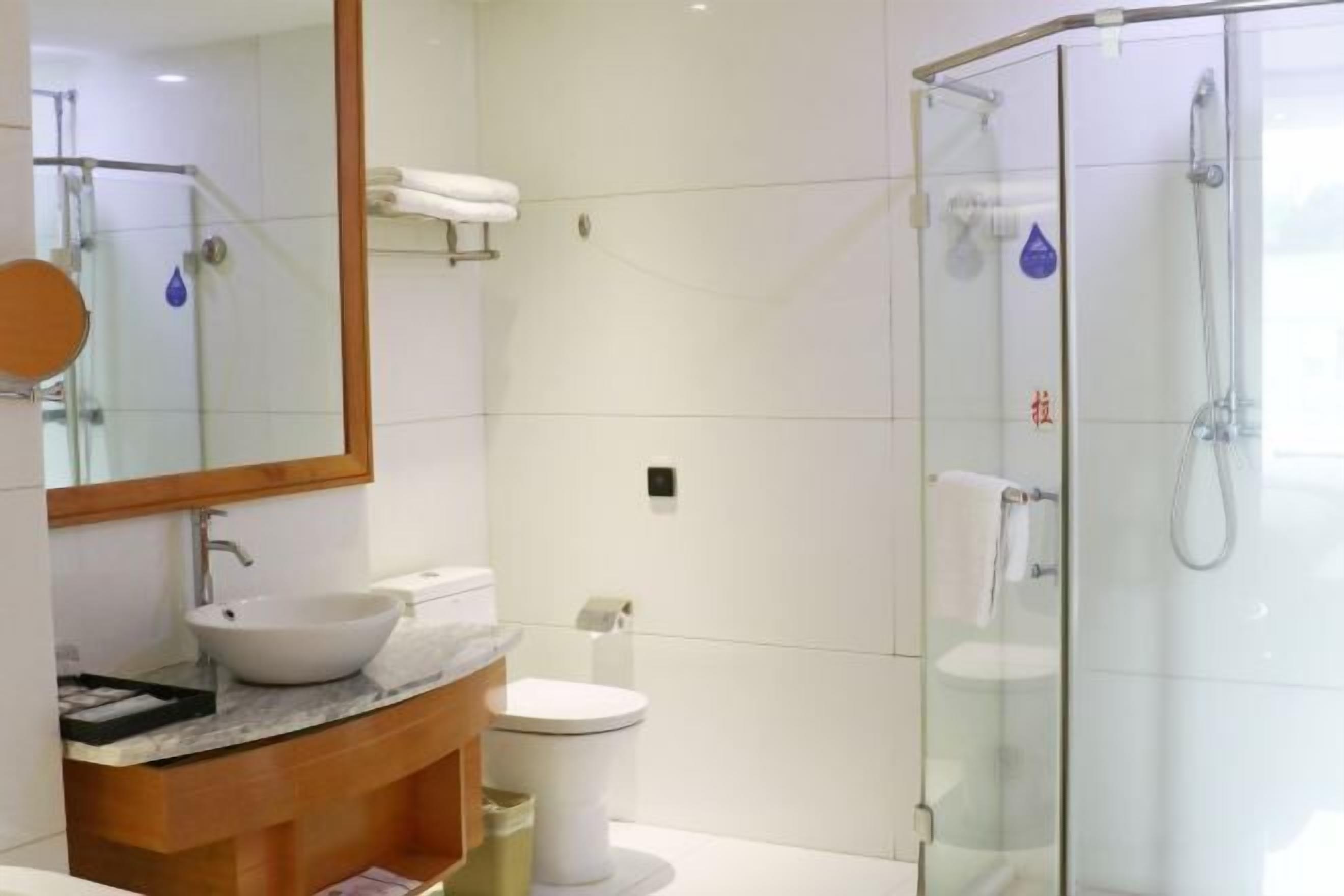 A modern bathroom with a glass-enclosed shower, a white sink, and a toilet.