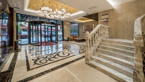 Eine Hotelhalle mit Marmorboden, einer imposanten Treppe und einem Kronleuchter.