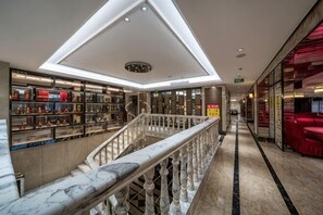 A hotel lobby with a marble staircase, a skylight, and a glass display case with items. - King du Hotel (Bus Station) (Nanping)