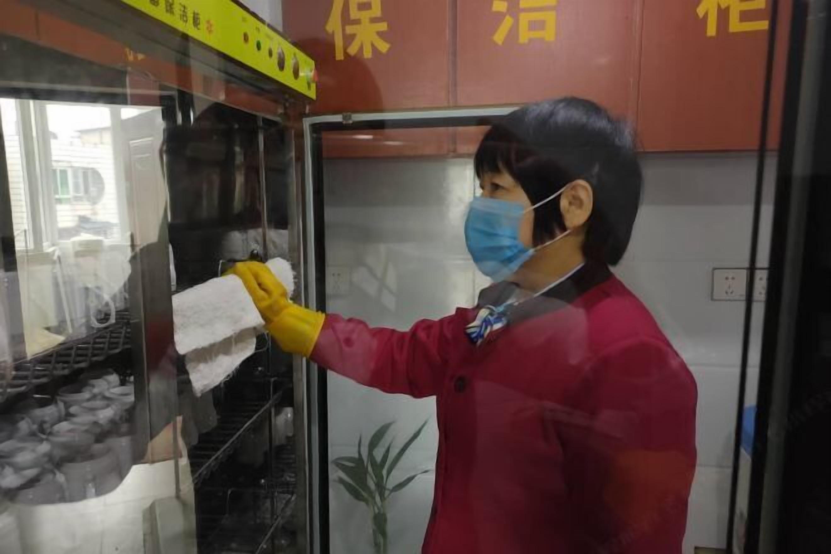 A person cleaning a glass enclosure with a yellow sign above.