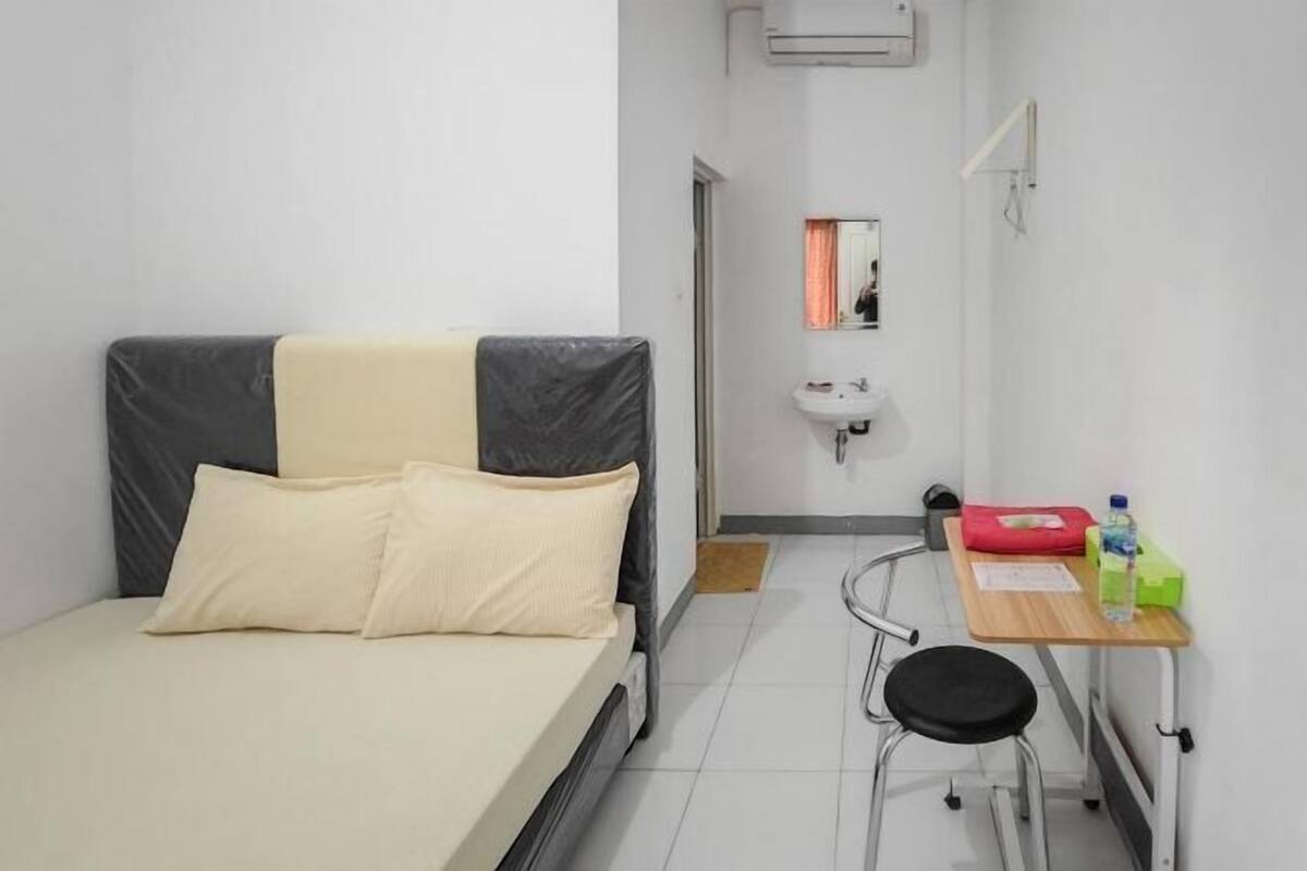 A small, clean room with a bed, a desk, and a mirror.