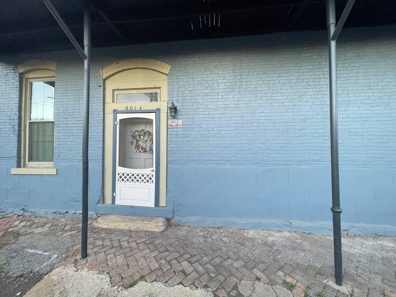 A building with a blue exterior, a white door with a decorative glass panel, and a small porch area.