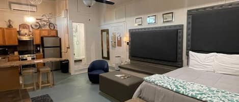A modern bedroom with a large bed, a TV, and a seating area with a sofa and ottoman.