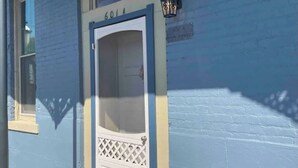A building with a blue exterior, a white door with a number '601' above it, and a small window to the left.
