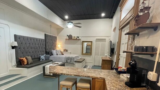 A modern kitchen with a central island, bar stools, a built-in sink, and a ceiling fan.