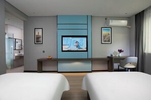 A modern hotel room with a flat-screen TV mounted on a blue wall, a small desk, a chair, and two beds. - Aste Meitu Hotel (Cultural Plaza Branch) (Yulin)