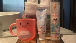 A bathroom with a pink mug, a tube of Protex, and a toothbrush.