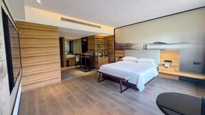 A modern hotel room with a large bed, a desk, and a painting on the wall. - Radow E Hotel (Wenzhou Chezhan Avenue Times Square Branch) (Wenzhou)