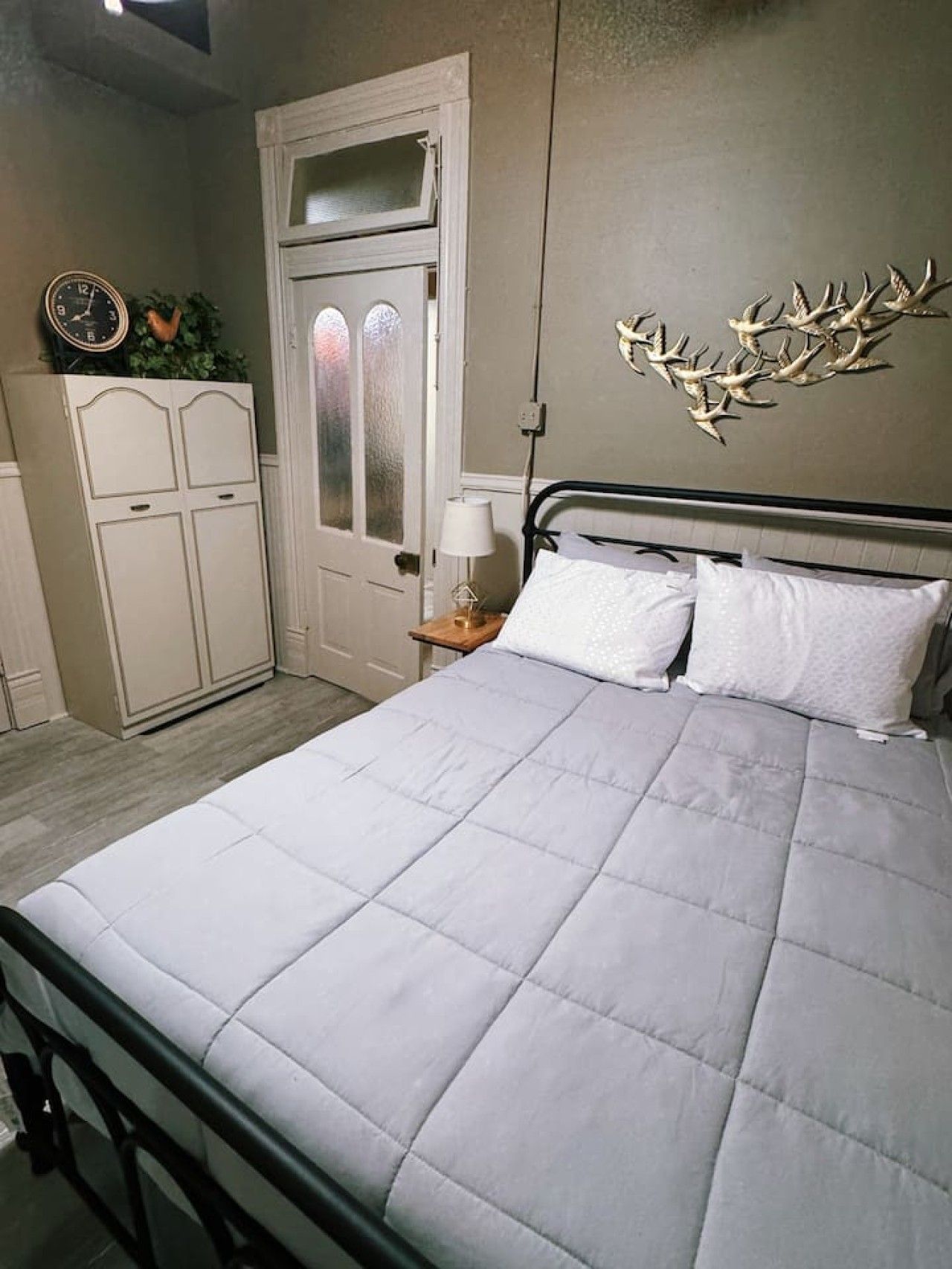 Une chambre à coucher comprenant un lit, une table de chevet, une commode et un élément décoratif mural.