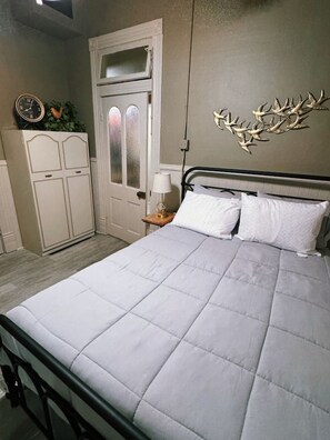Ein Schlafzimmer mit einem Bett, einem Nachttisch, einer Kommode und einem Wandbild.