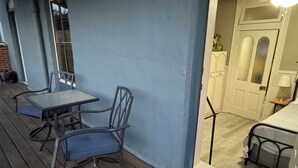 Eine Holzterrasse mit Tisch und Stühlen, eine Tür zu einem Innenraum sowie ein kleiner Teppich am Eingang.