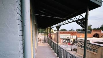 A covered outdoor area with a metal railing, a stop sign, and a building in the background.