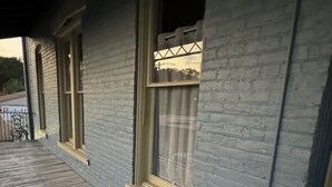 Ein Gebäude mit einer Holzterrasse und einem Fenster mit einem Metallgitter.