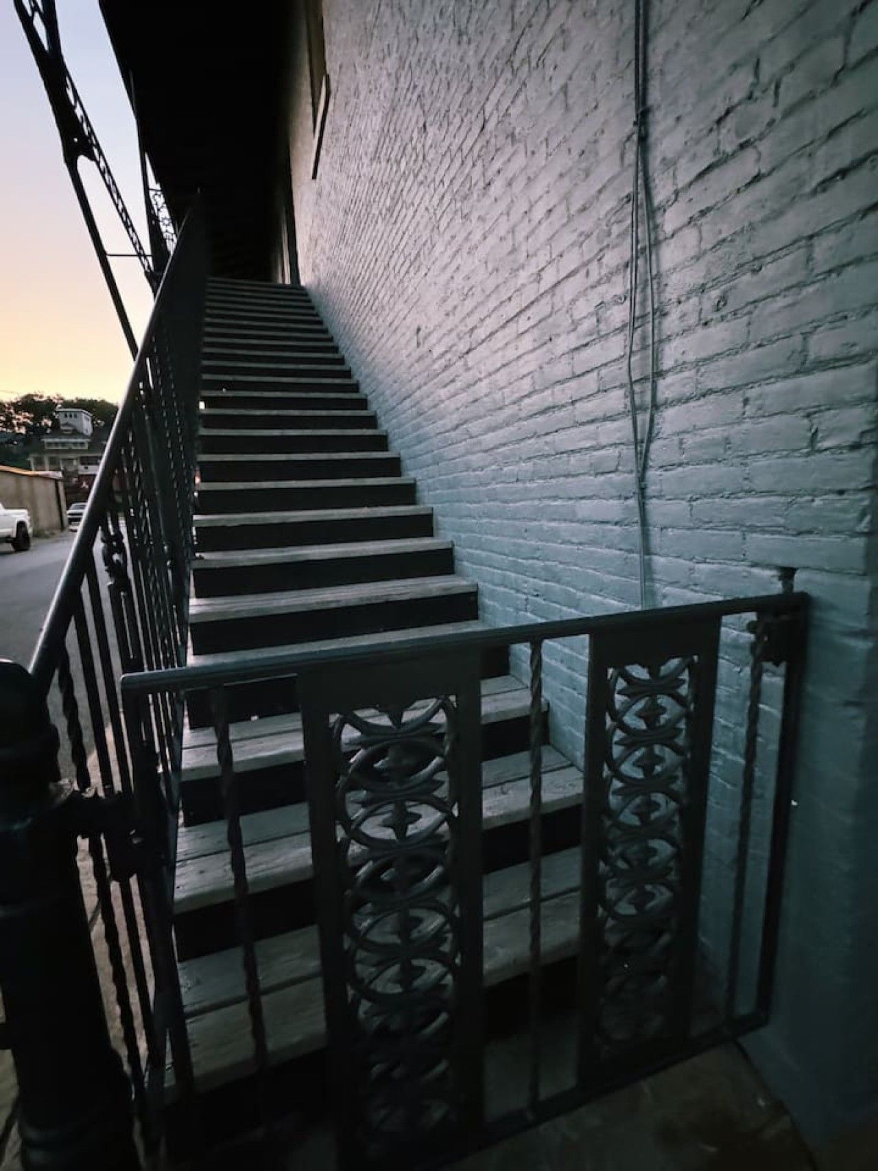 Un escalier avec des rampes en métal et un mur en briques blanches.