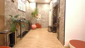 A hotel lobby with marble walls, a wooden floor, a reception desk, a plant, a pink exercise ball, and a trash bin. - fuerte-hotel (Yueqing)
