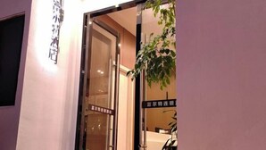 A hotel entrance with a glass door, a sign indicating the hotel name, and a reflection of the interior. - fuerte-hotel (Yueqing)