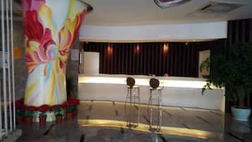 A reception area with a large floral mural, a reception desk, and two bar stools.