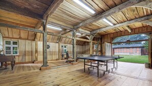 Une pièce spacieuse avec un plancher en bois, une table de ping-pong et de grandes fenêtres.