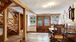 Un escalier en bois, un coin repas avec des chaises et une table, et une paire de portes-fenêtres.