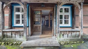 Une entrée en bois avec un porche en bois, un mur en briques et une fenêtre à cadre bleu.