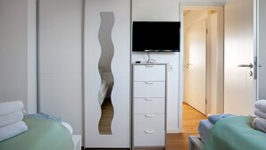 A hotel room with a bed, a wardrobe with a unique design, a television, and a bathroom door. - Apartment 'Edda 3' with Shared Garden, Balcony and Wi-Fi (Meldorf)