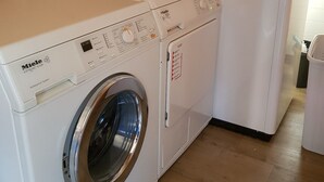 A white Miele washing machine in a room with wooden flooring and a wooden wall. - Holiday Home 'Wolfshütte' with Private Terrace, Garden and Wi-Fi (Hillesheim)