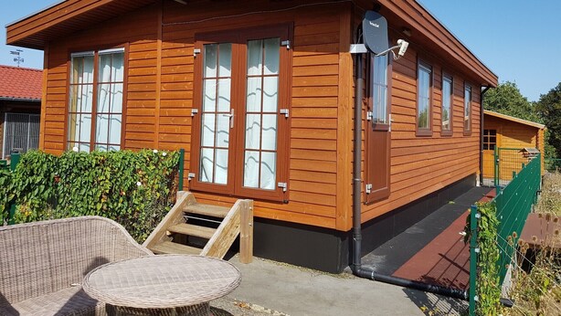 A wooden cabin with large windows, a small porch, and a staircase leading to the entrance. - Holiday Home 'Wolfshütte' with Private Terrace, Garden and Wi-Fi (Hillesheim)