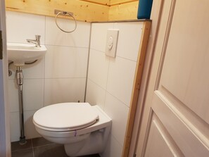 A small bathroom with a toilet, sink, and shower.