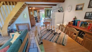 Ein gemütliches Wohnzimmer mit einem Holzesstisch, einer Couch und einer Treppe, die in ein Obergeschoss führt.