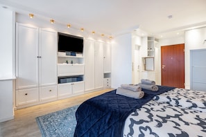 Une chambre à coucher avec un lit, une armoire, une télévision et une porte.