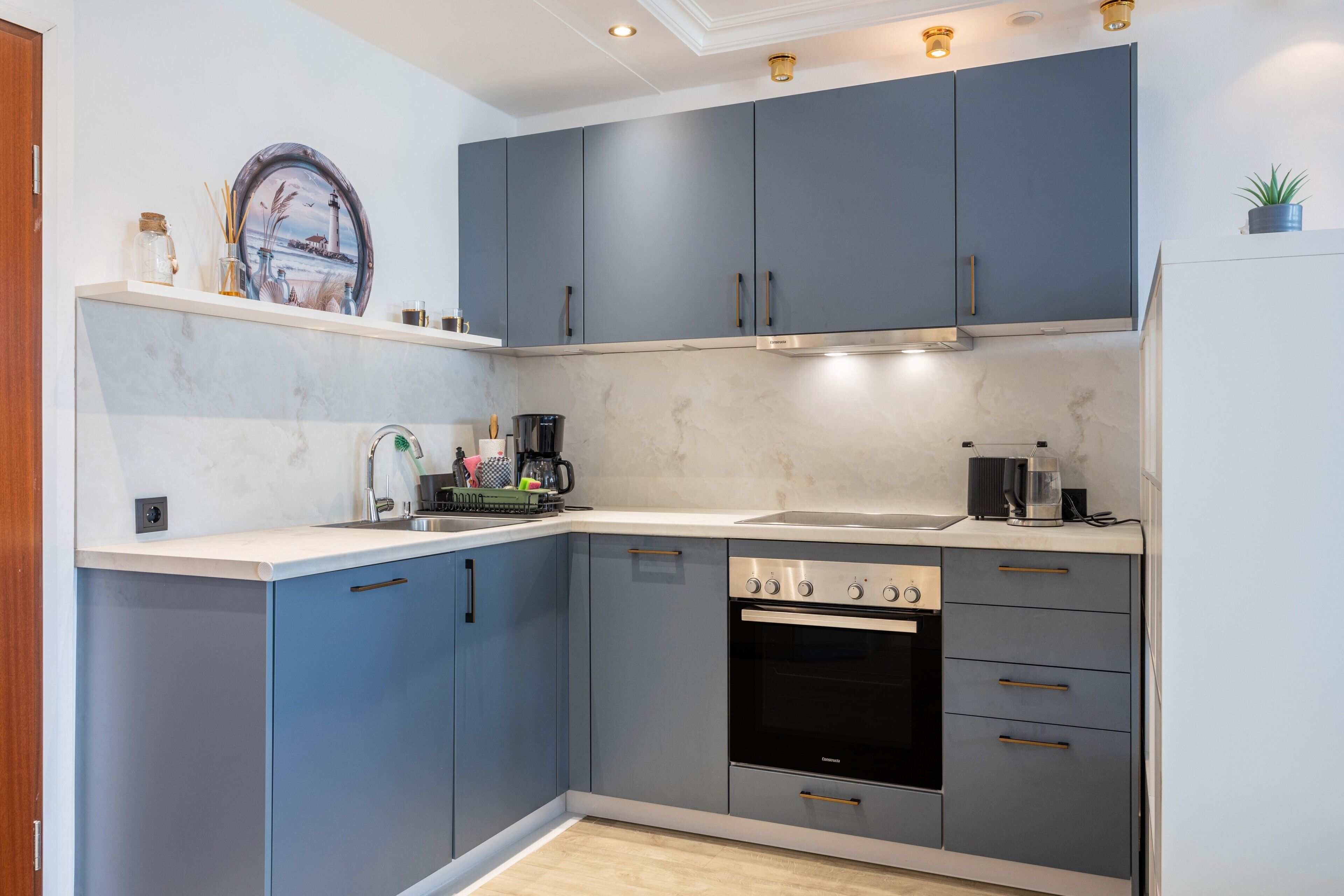 A modern kitchen with grey cabinets, a built-in oven, and a countertop with a coffee maker.