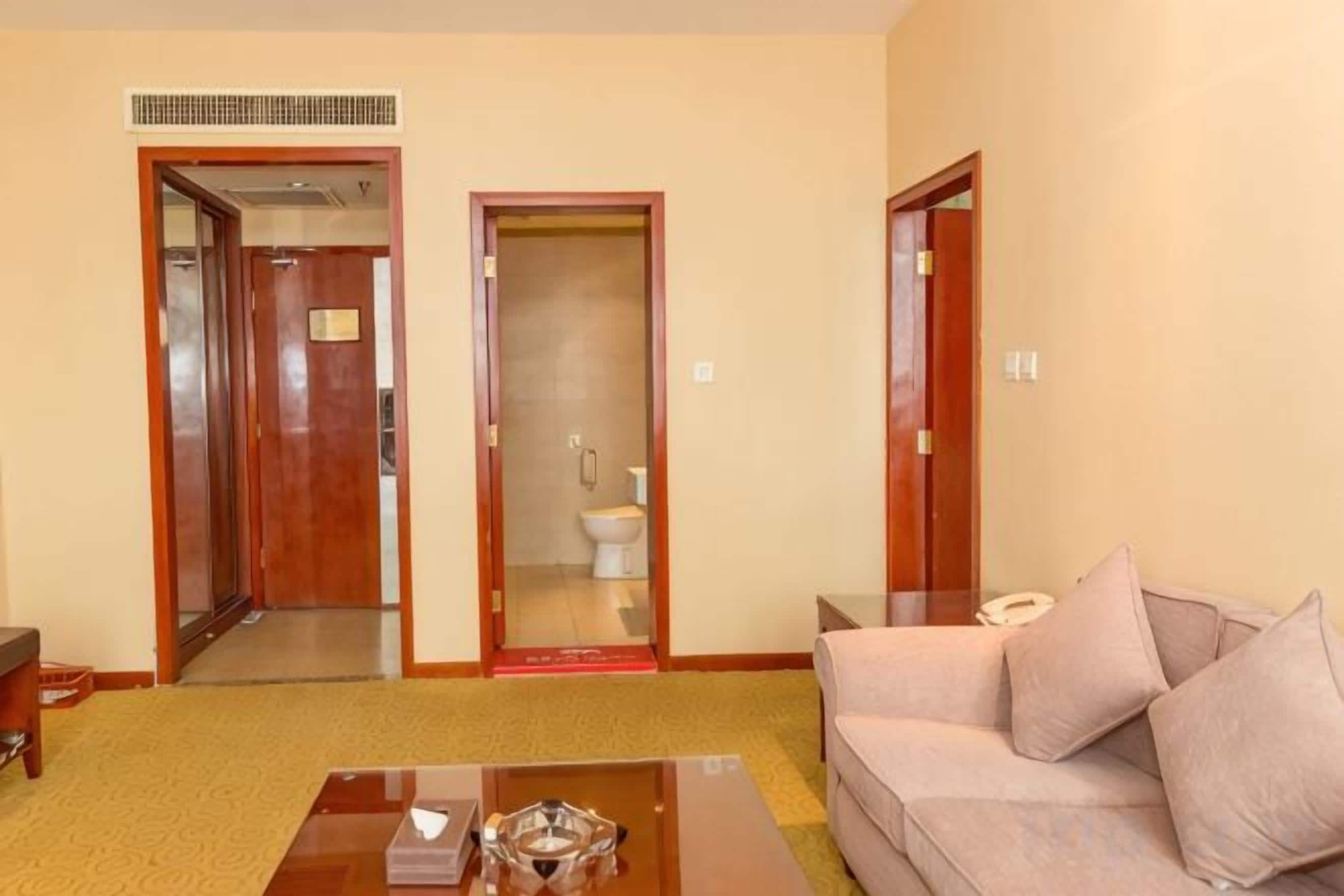 A living room with a sofa, a coffee table, and a door leading to a bathroom.