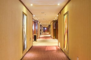 A hotel hallway with a carpeted floor, wooden doors, and framed artwork on the walls. - Yongji Haina International Hotel (Yongji)