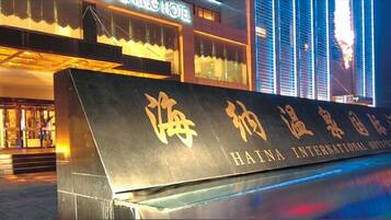 A hotel entrance with a large sign displaying the name 'HAINA INTERNATIONAL HOTEL' in gold lettering.