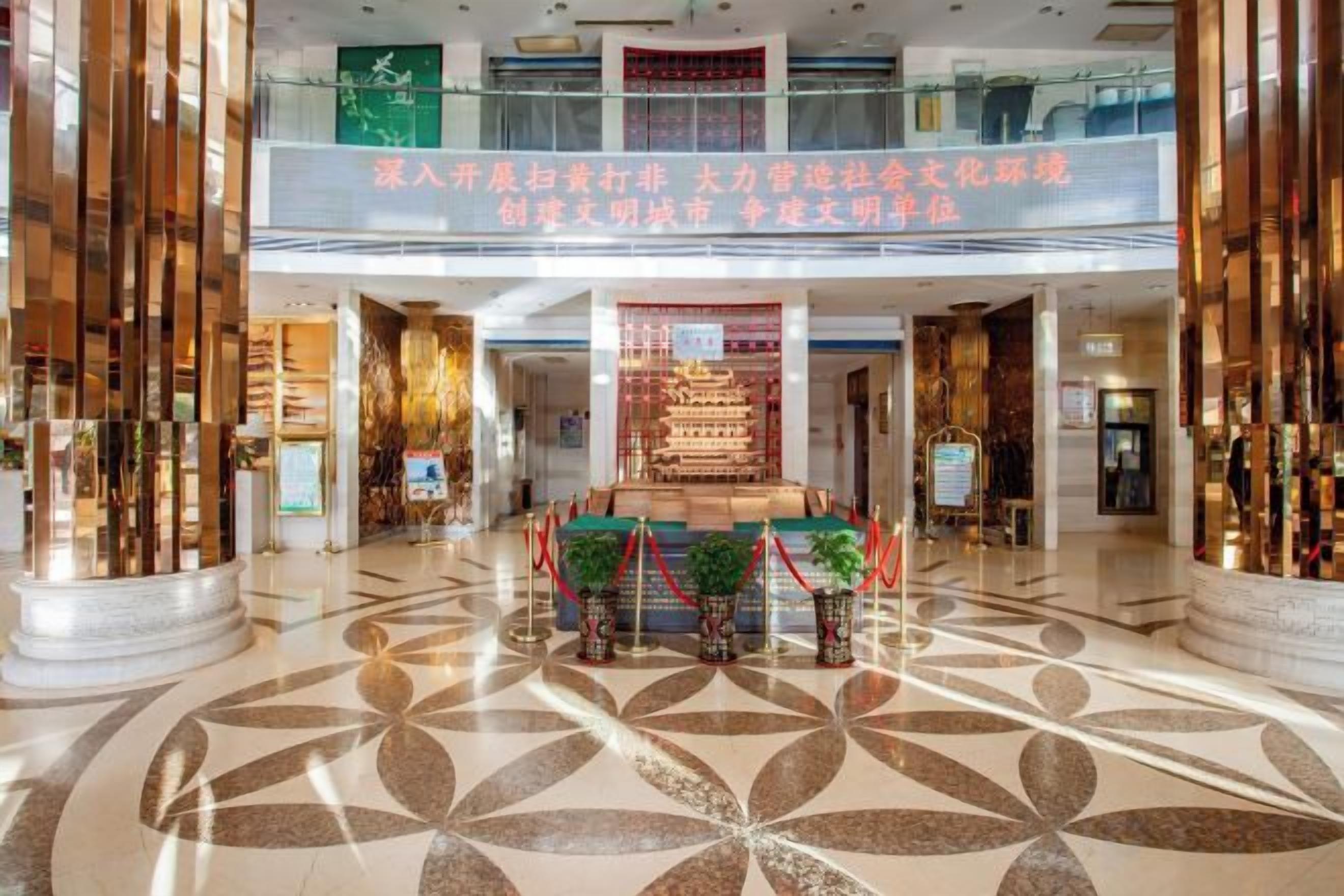 A spacious lobby with a high ceiling, a central decorative fountain, and a patterned floor.