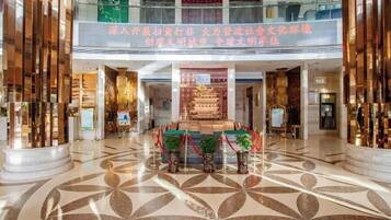 A spacious lobby with a high ceiling, a central decorative fountain, and a patterned floor.