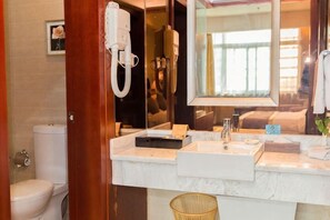 Une salle de bain équipée de toilettes, d’un lavabo, d’un miroir et d’un sèche-cheveux.