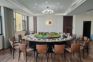 A conference room with a round table, chairs, and a chandelier.