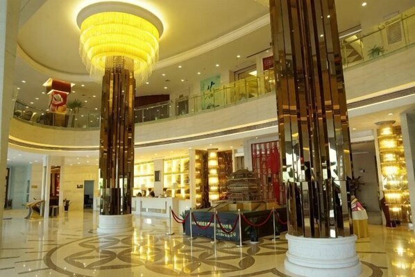 A spacious lobby with a high ceiling, a central column, and a reception desk. - Yongji Haina International Hotel (Yongji)