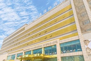 Un hôtel à plusieurs étages doté d’une architecture moderne, avec une entrée imposante, un auvent et de grandes fenêtres.