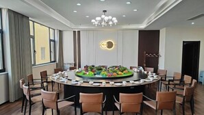 A conference room with a round table, chairs, a chandelier, and a decorative centerpiece. - Yongji Haina International Hotel (Yongji)