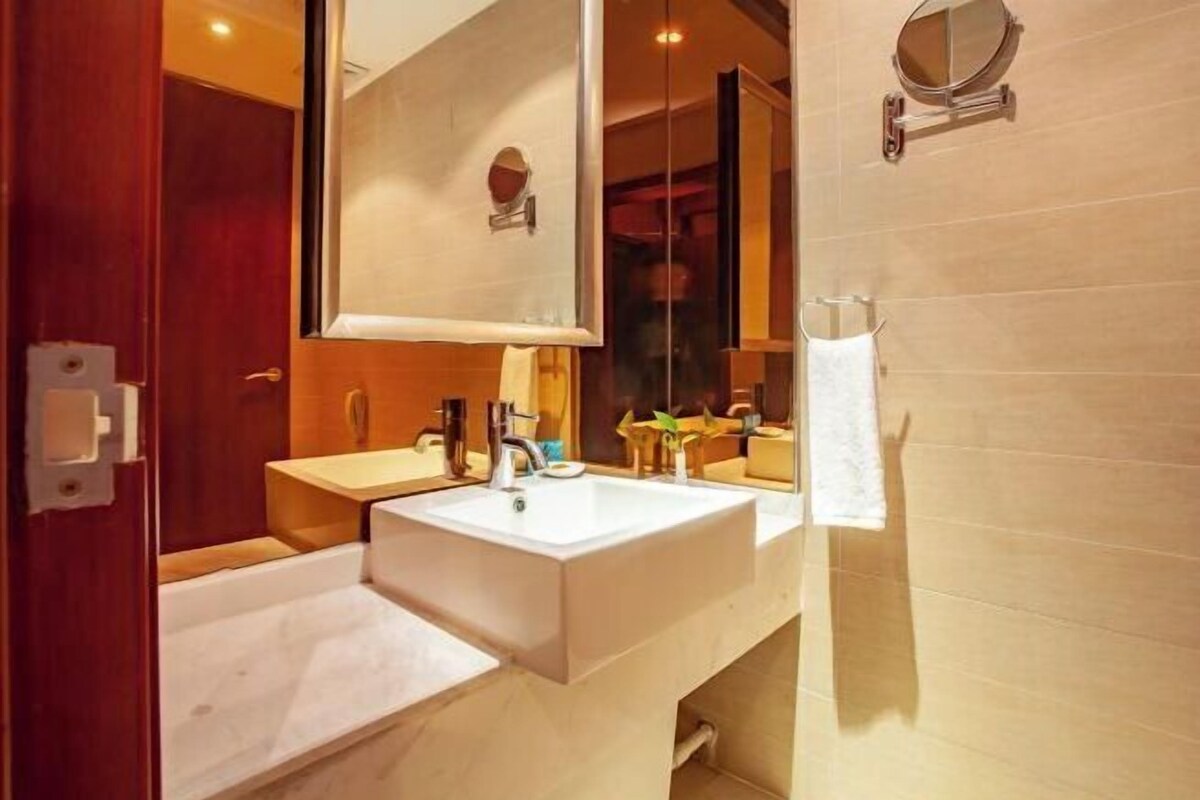 A modern bathroom with a large sink, a mirror, and a towel rack.